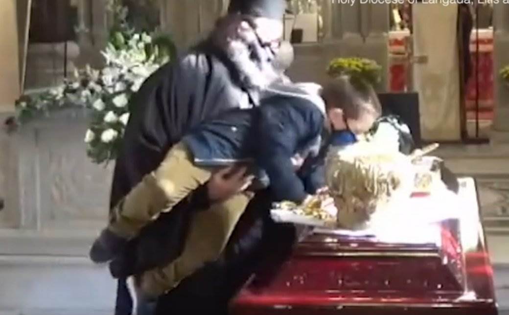  SVIJET UŽASNUT POSTUPKOM GRČKOG SVEŠTENIKA: Podigao dječaka da poljubi kovčeg vladike koji je umro od KORONE (VIDEO) 